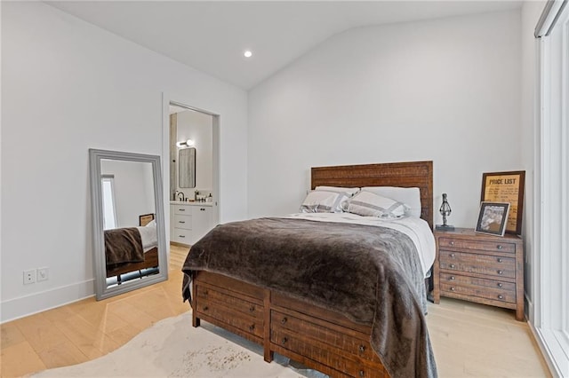 bedroom featuring vaulted ceiling, light hardwood / wood-style floors, and ensuite bath