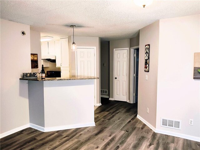 unfurnished bedroom with ceiling fan, dark hardwood / wood-style floors, a walk in closet, and a textured ceiling