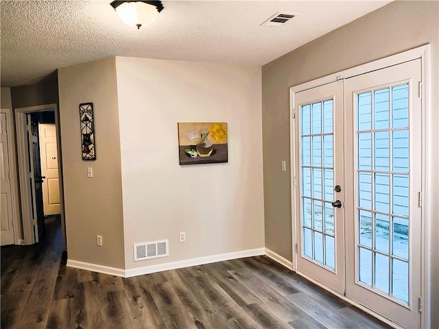 doorway with dark wood-type flooring, a textured ceiling, and french doors