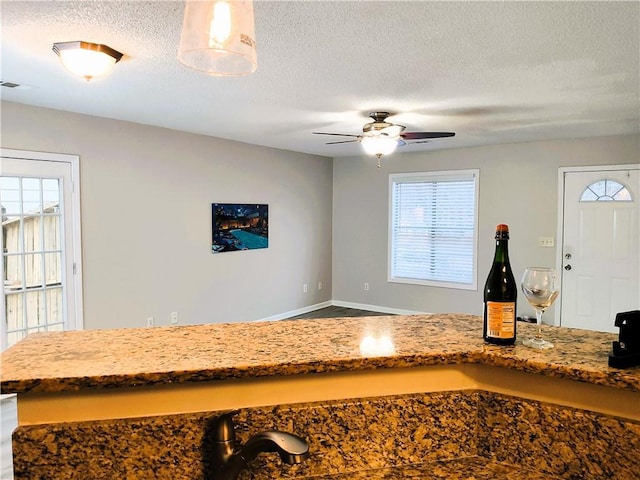 room details with a textured ceiling, ceiling fan, and indoor bar