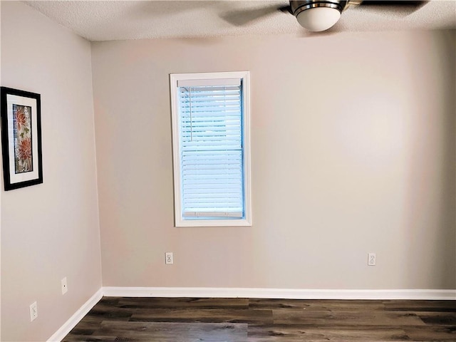 unfurnished room with a textured ceiling, a wealth of natural light, dark wood-type flooring, and ceiling fan