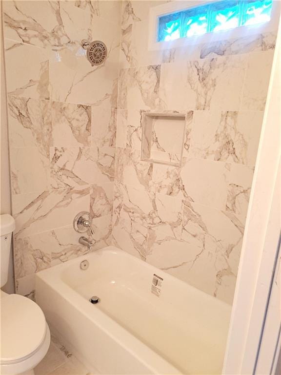 bathroom featuring tile patterned floors, toilet, and tiled shower / bath