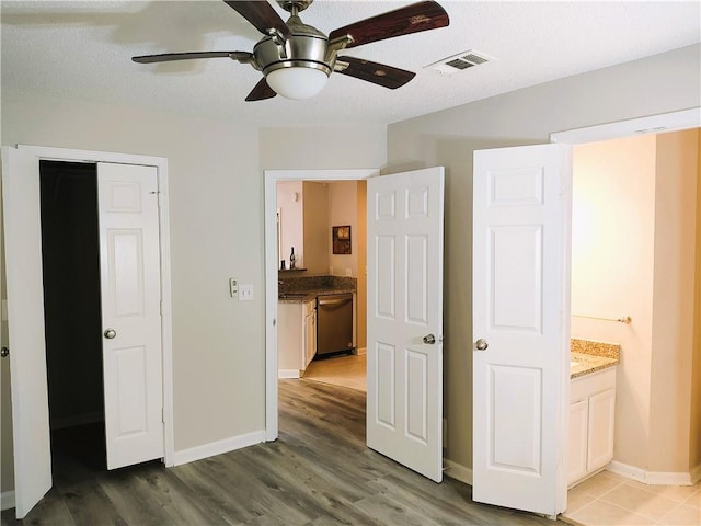 unfurnished bedroom featuring ceiling fan, a closet, connected bathroom, and hardwood / wood-style flooring