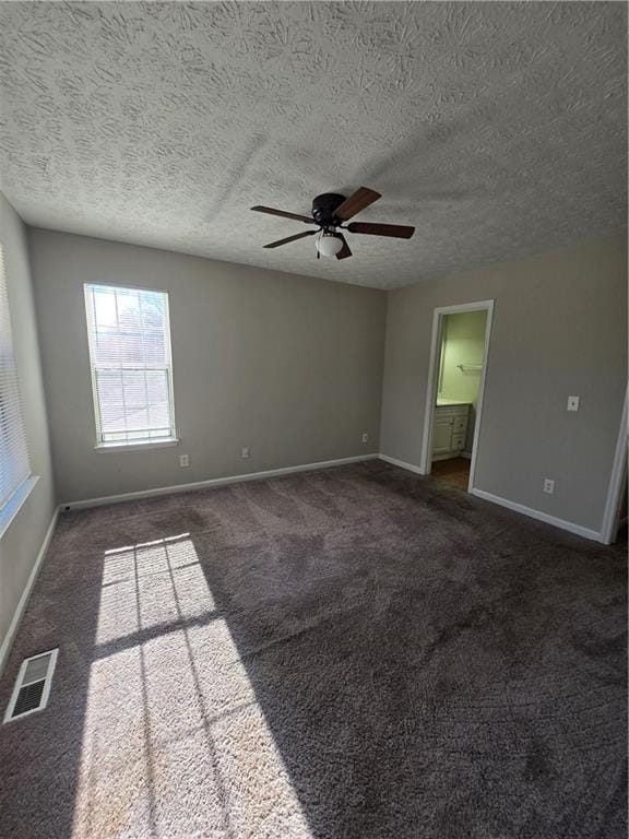 carpeted spare room featuring ceiling fan and a textured ceiling