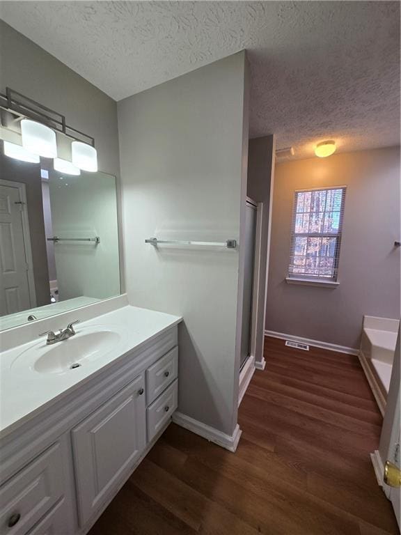 bathroom featuring shower with separate bathtub, vanity, a textured ceiling, and hardwood / wood-style flooring