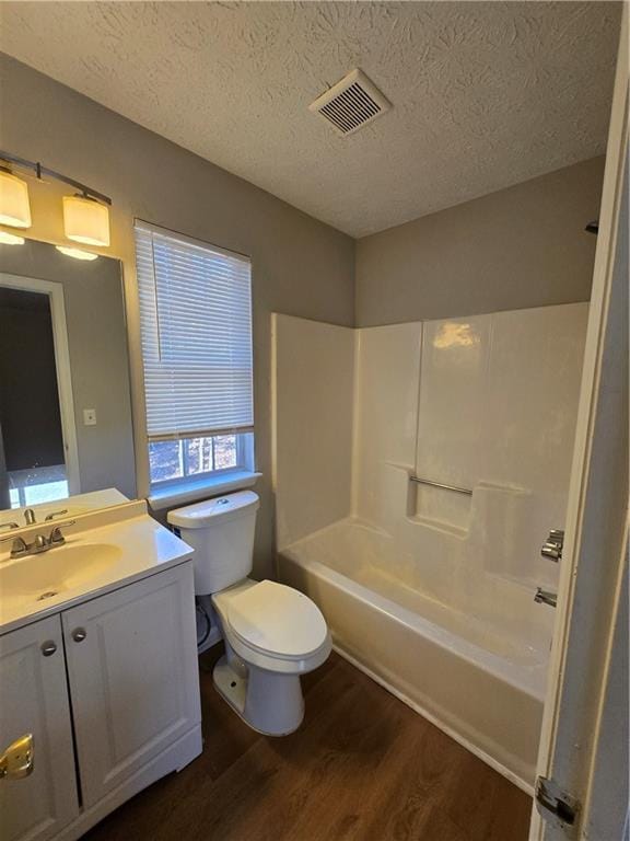 full bathroom with vanity, wood-type flooring, a textured ceiling, and toilet