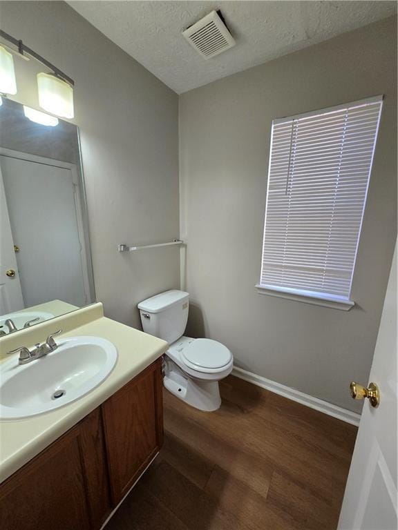 bathroom with hardwood / wood-style flooring, vanity, toilet, and a textured ceiling