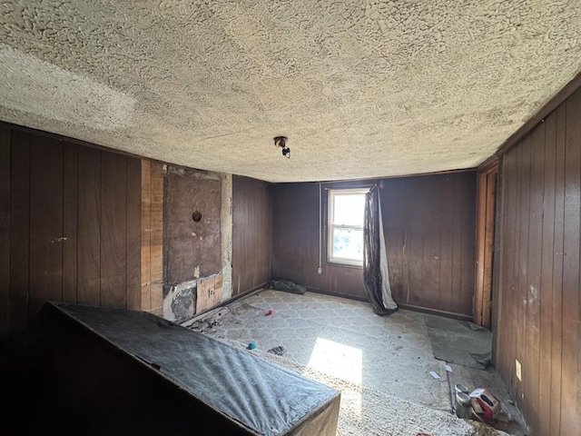 unfurnished bedroom featuring a textured ceiling and wooden walls