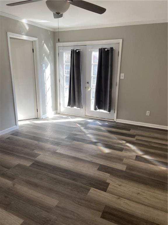 spare room featuring baseboards, ornamental molding, ceiling fan, and dark wood-style flooring