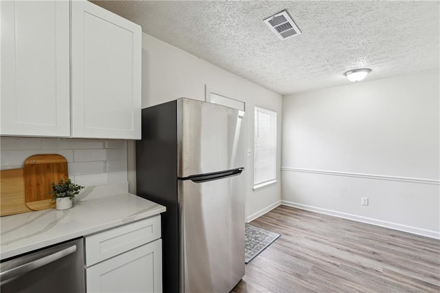 4282 Worth St NW, Acworth, GA 30101 - kitchen with decorative backsplash, appliances with stainless steel finishes, light wood-style flooring, white cabinetry, and visible vents