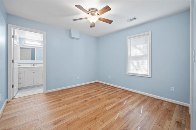 empty room featuring ceiling fan, sink, and light wood-type flooring