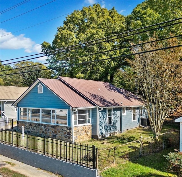 view of front of house with central AC and a front yard