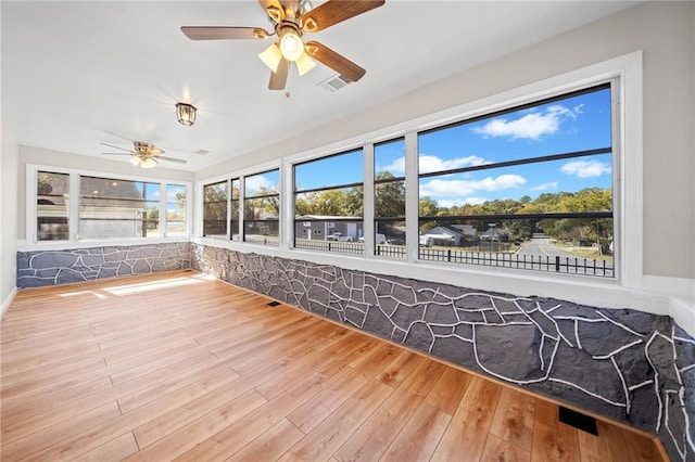 unfurnished sunroom with ceiling fan