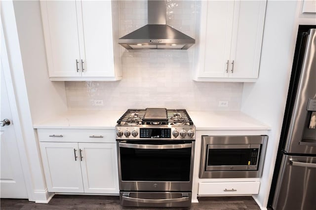 kitchen with appliances with stainless steel finishes, white cabinetry, light stone counters, decorative backsplash, and wall chimney exhaust hood