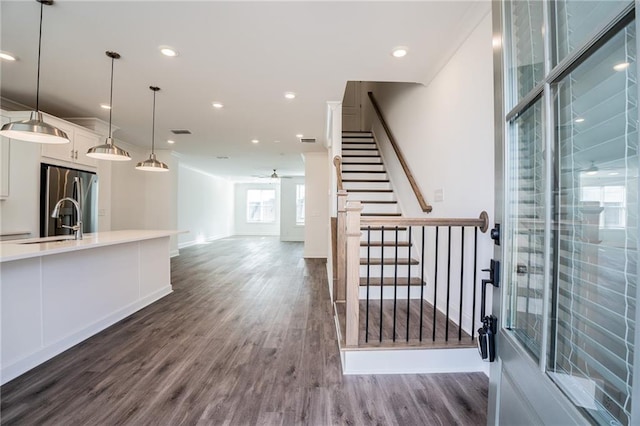 interior space featuring decorative light fixtures, white cabinets, dark hardwood / wood-style flooring, ceiling fan, and stainless steel fridge with ice dispenser