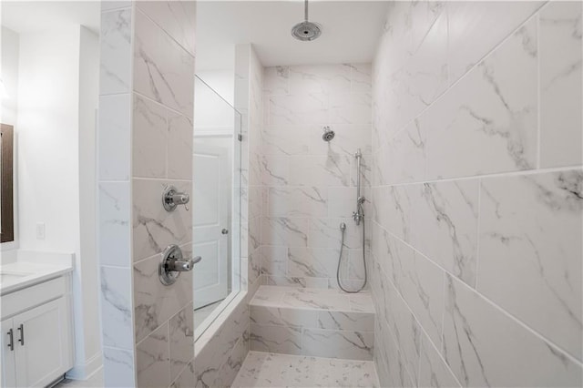 bathroom with a tile shower and vanity