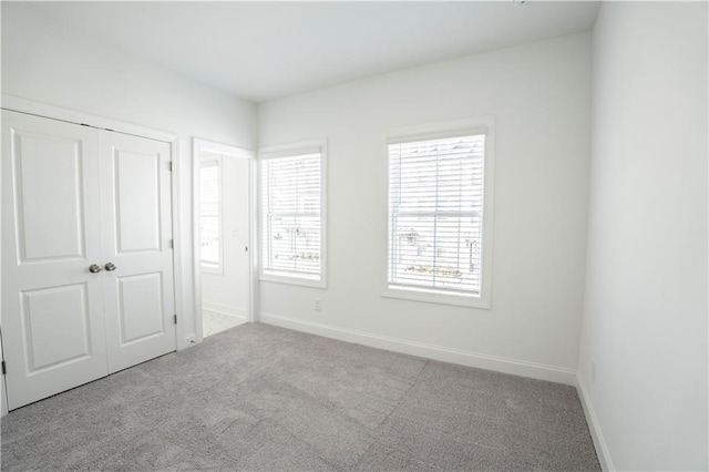 unfurnished bedroom with light carpet and a closet