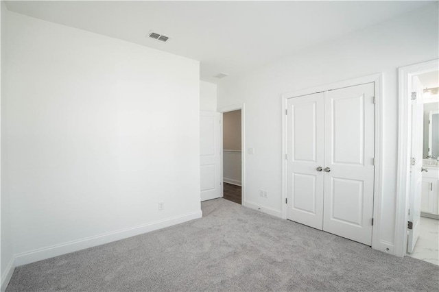 unfurnished bedroom with connected bathroom, light colored carpet, and a closet