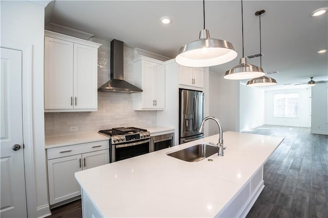 kitchen with pendant lighting, sink, appliances with stainless steel finishes, white cabinets, and wall chimney exhaust hood