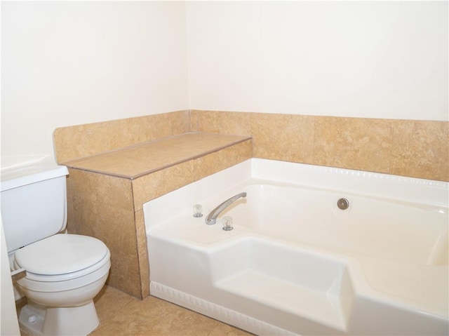 bathroom with toilet, a tub to relax in, and tile patterned floors