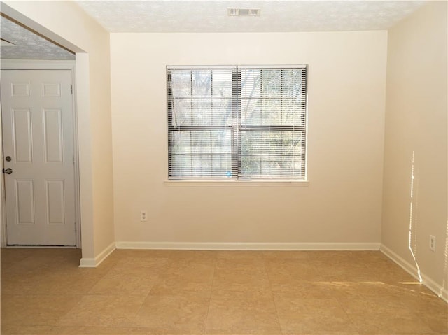 tiled empty room featuring a textured ceiling