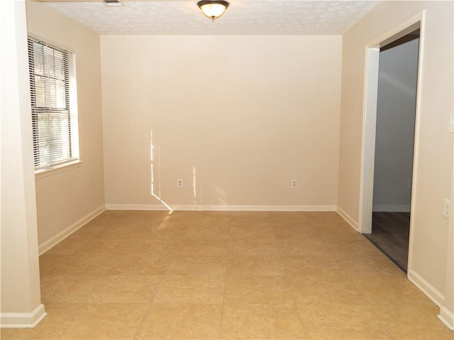 unfurnished room with light tile patterned floors and a textured ceiling