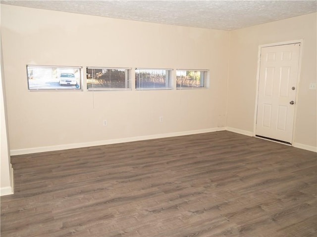 spare room featuring a textured ceiling and dark hardwood / wood-style floors