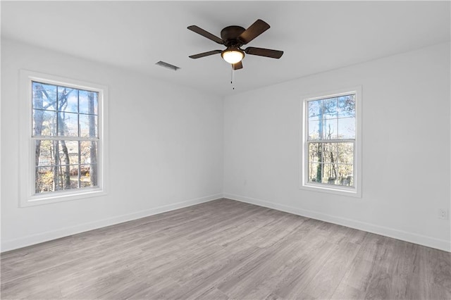 spare room featuring visible vents, a ceiling fan, baseboards, and wood finished floors