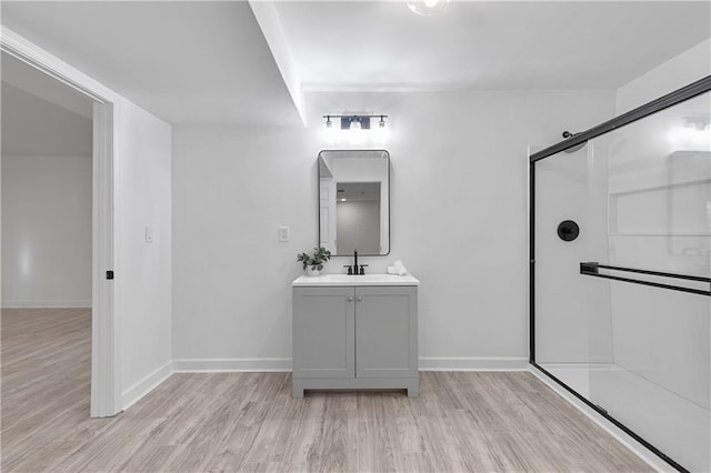 full bathroom with vanity, a shower stall, wood finished floors, and baseboards