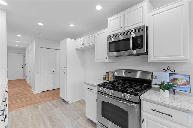 kitchen with recessed lighting, light wood-style floors, appliances with stainless steel finishes, white cabinetry, and backsplash