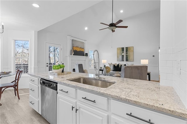 kitchen featuring light stone countertops, dishwasher, white cabinets, a ceiling fan, and a sink