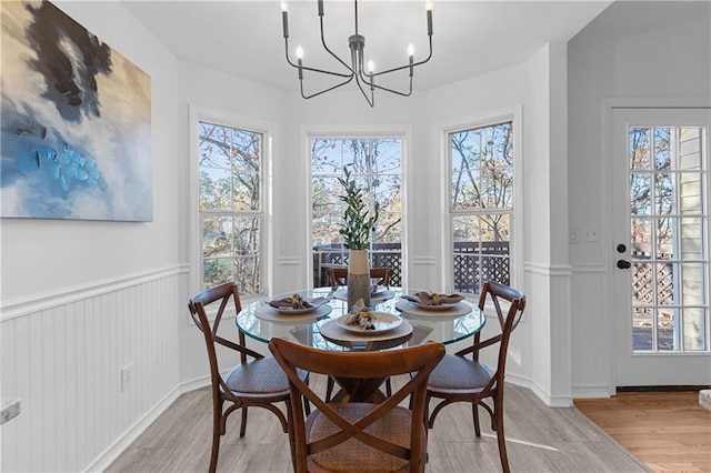 dining room with a notable chandelier, a wainscoted wall, and light wood finished floors