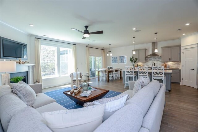 living room with ceiling fan, dark hardwood / wood-style flooring, sink, and crown molding