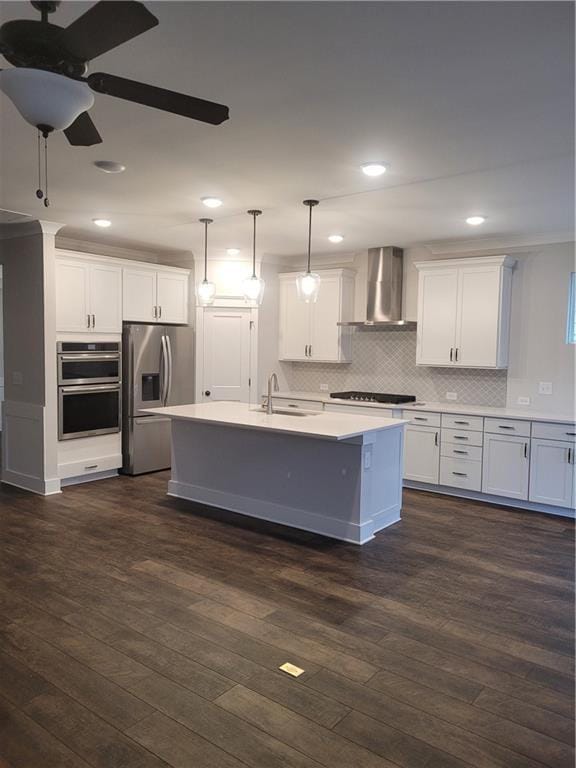 kitchen featuring wall chimney range hood, dark hardwood / wood-style floors, decorative light fixtures, white cabinets, and appliances with stainless steel finishes