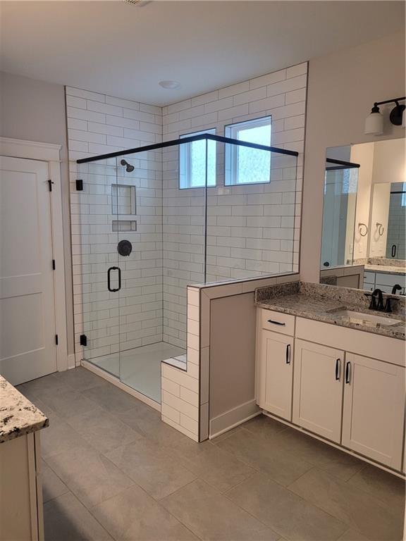 bathroom featuring tile patterned flooring, vanity, and walk in shower