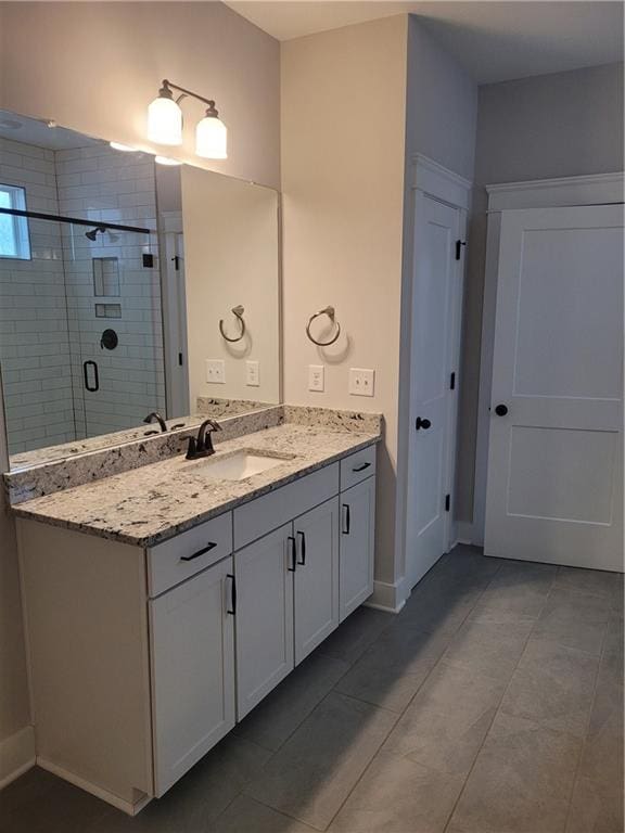 bathroom with tile patterned floors, vanity, and a shower with door