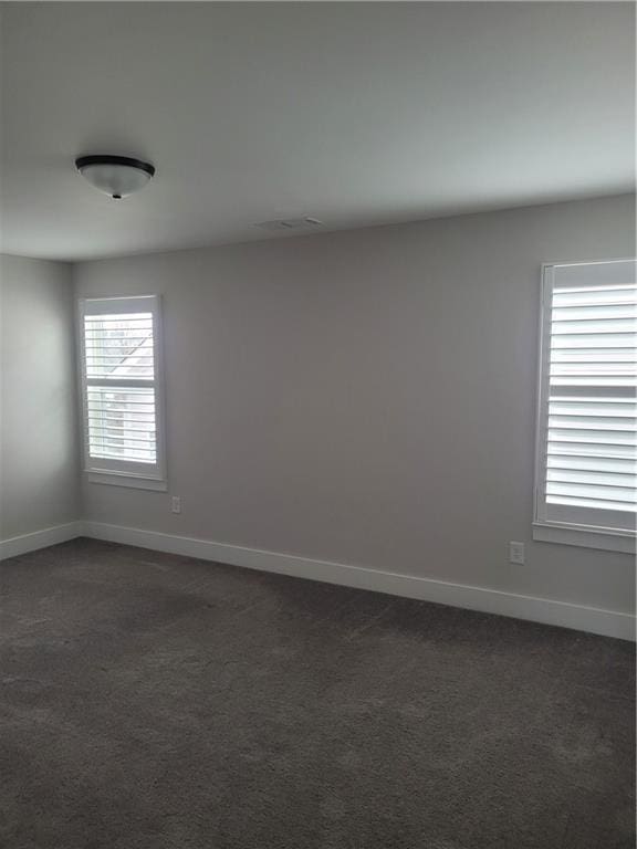 unfurnished room featuring dark colored carpet