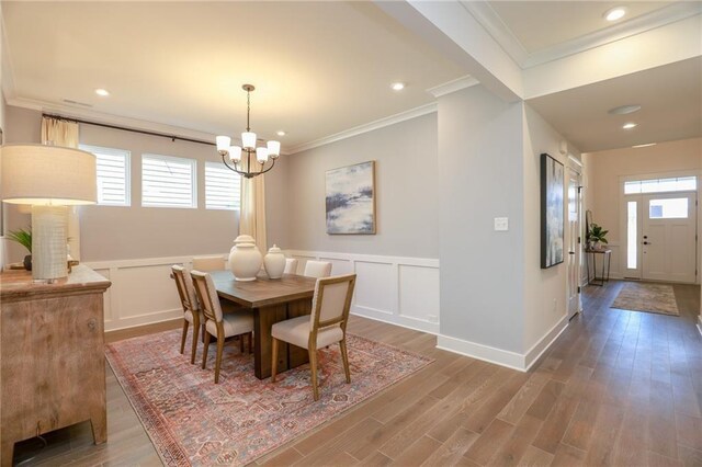 dining space with crown molding, hardwood / wood-style floors, and a chandelier