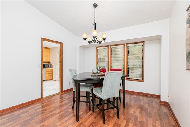 4065 Maxanne Dr NW, Kennesaw, GA 30144 - dining space featuring wood finished floors, lofted ceiling, baseboards, and an inviting chandelier