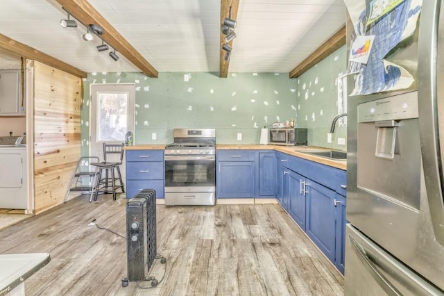 kitchen with blue cabinetry, stainless steel appliances, light wood-style floors, and a sink