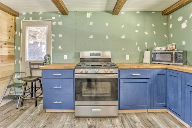 kitchen with blue cabinetry, appliances with stainless steel finishes, and wood counters