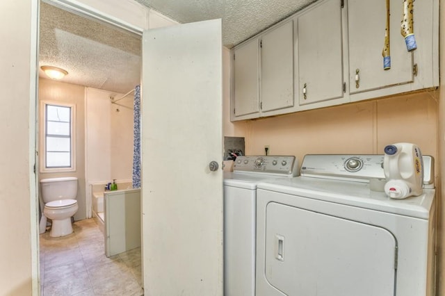 laundry area featuring a textured ceiling, light tile patterned floors, and washer and clothes dryer