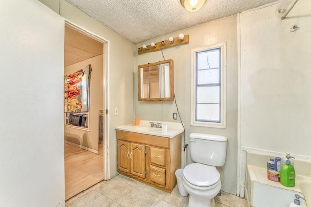 bathroom featuring a textured ceiling, vanity, and toilet