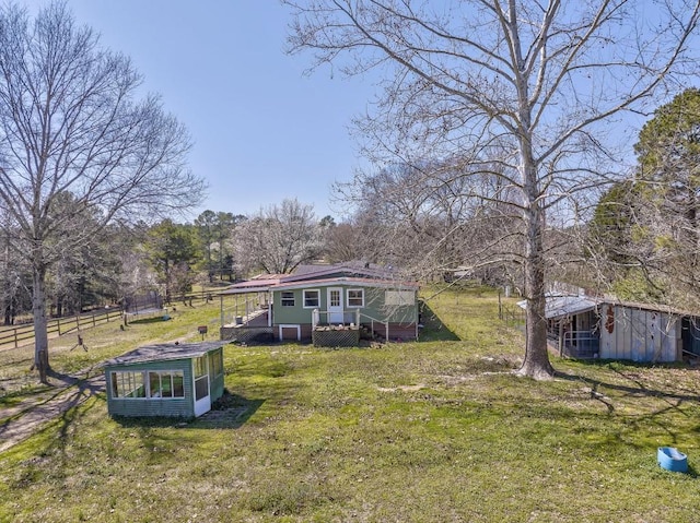 exterior space featuring an outdoor structure, a lawn, fence, and a wooden deck