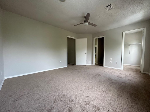 unfurnished bedroom with carpet flooring, ceiling fan, a spacious closet, a textured ceiling, and a closet