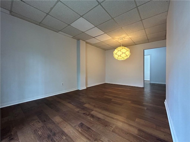 spare room featuring a paneled ceiling and dark hardwood / wood-style flooring