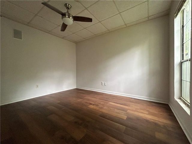 spare room with dark hardwood / wood-style flooring, a drop ceiling, and ceiling fan