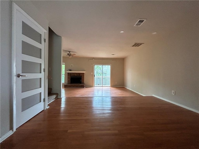 unfurnished living room with a fireplace, dark hardwood / wood-style flooring, and ceiling fan