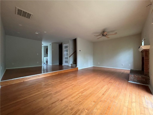 unfurnished living room with ceiling fan, wood-type flooring, and a fireplace