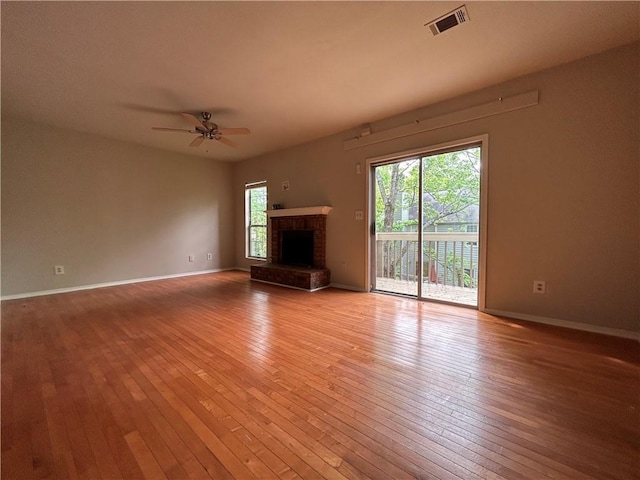 unfurnished living room with light hardwood / wood-style floors, a brick fireplace, and ceiling fan